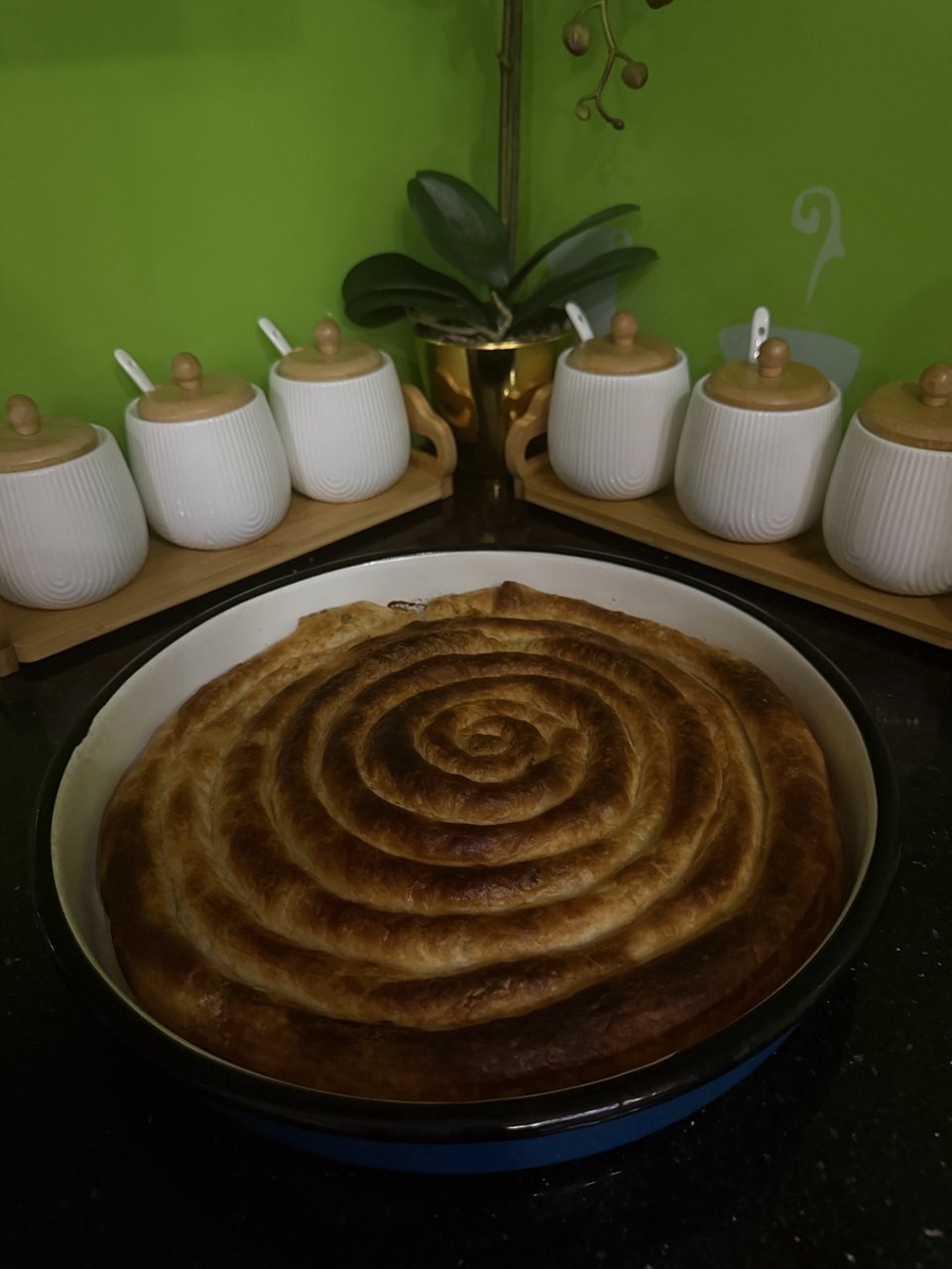 Domaća pita sa mesom, svježe pečena, spiralno savijena u tepsiji